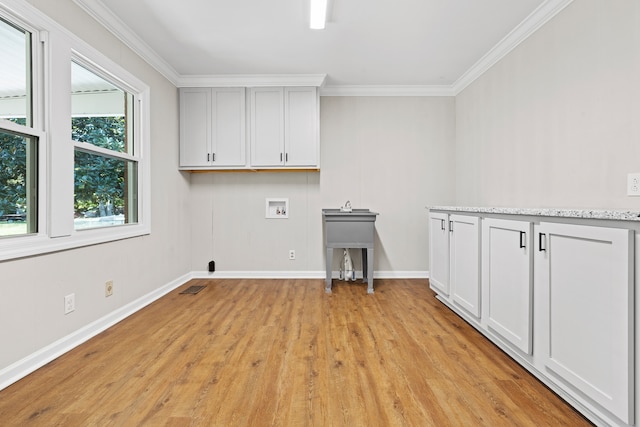 laundry room featuring washer hookup, crown molding, cabinets, and light wood-type flooring