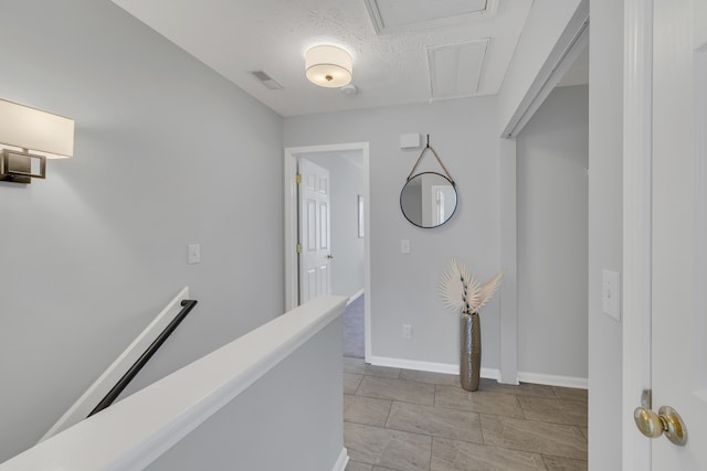 hall featuring a textured ceiling and light tile patterned flooring