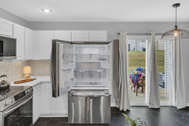 kitchen with dark tile patterned floors, stainless steel appliances, white cabinets, pendant lighting, and backsplash