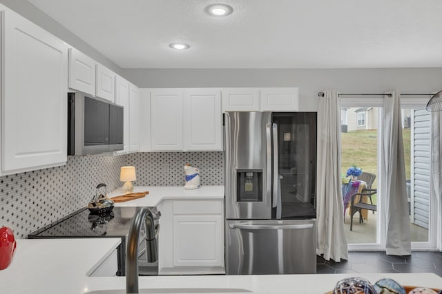 kitchen featuring decorative backsplash, dark tile patterned floors, sink, stainless steel appliances, and white cabinets