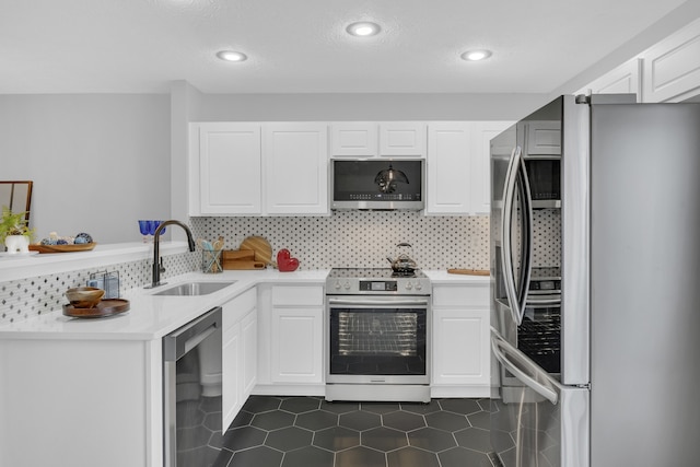 kitchen with decorative backsplash, dark tile patterned floors, sink, stainless steel appliances, and white cabinetry