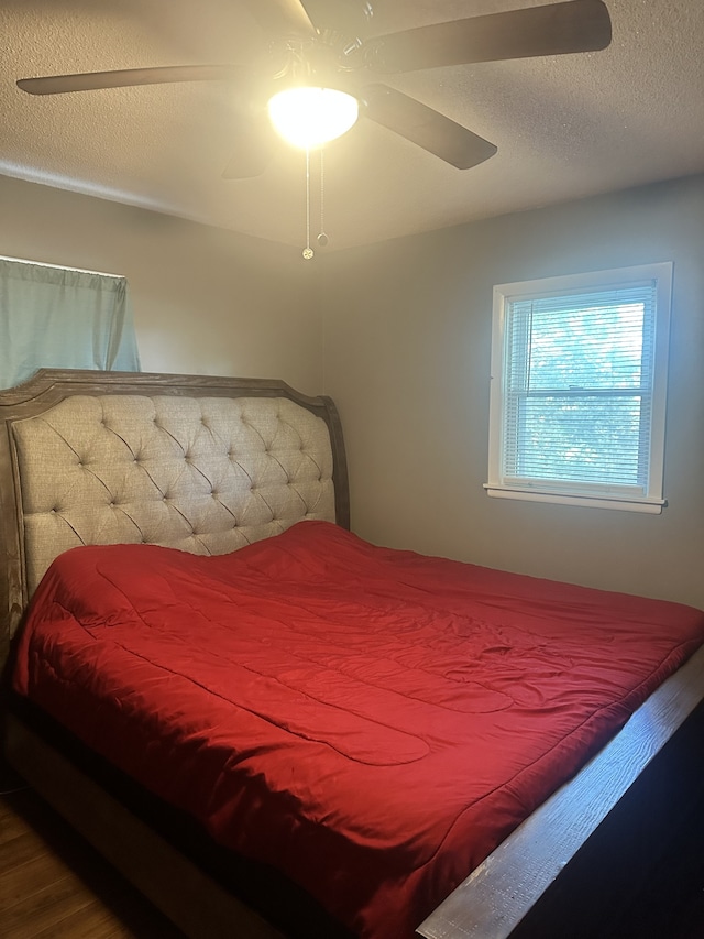 bedroom featuring ceiling fan, hardwood / wood-style floors, and a textured ceiling