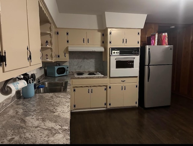 kitchen featuring sink, dark hardwood / wood-style flooring, backsplash, white appliances, and cream cabinetry