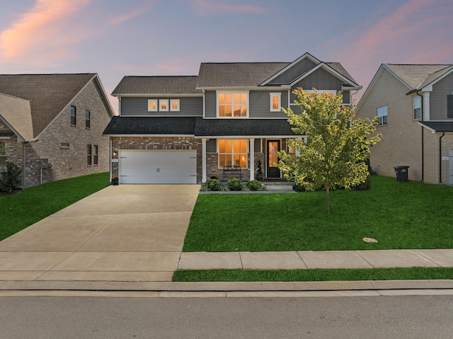 view of front facade with covered porch, a garage, and a lawn