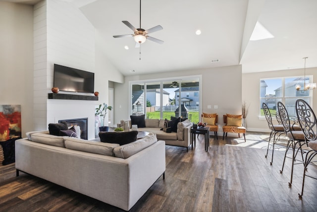 living room featuring dark wood-type flooring, high vaulted ceiling, a healthy amount of sunlight, and a large fireplace