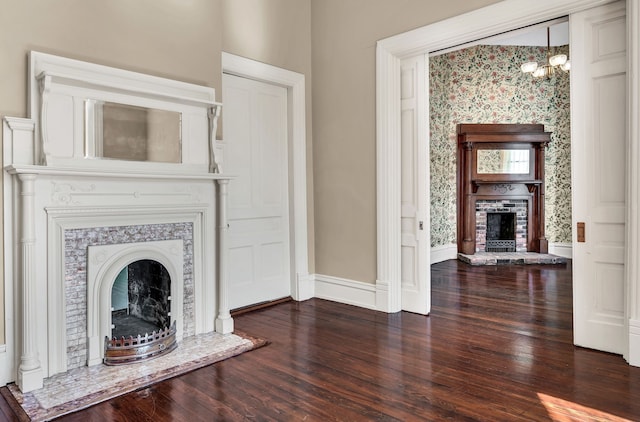 unfurnished living room featuring an inviting chandelier and dark hardwood / wood-style flooring