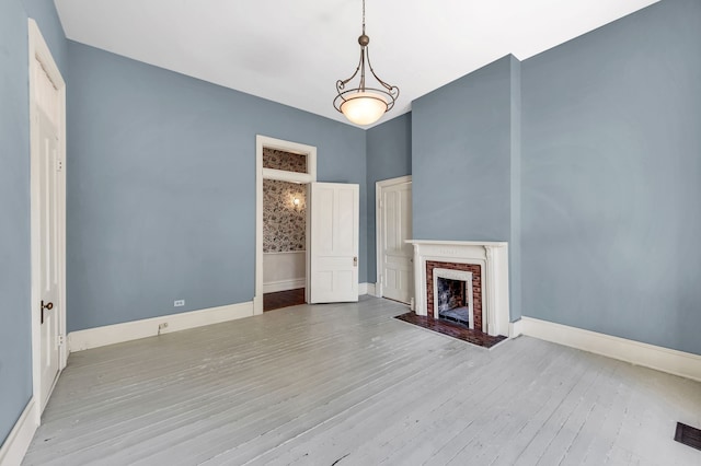 unfurnished living room with a brick fireplace and light hardwood / wood-style floors