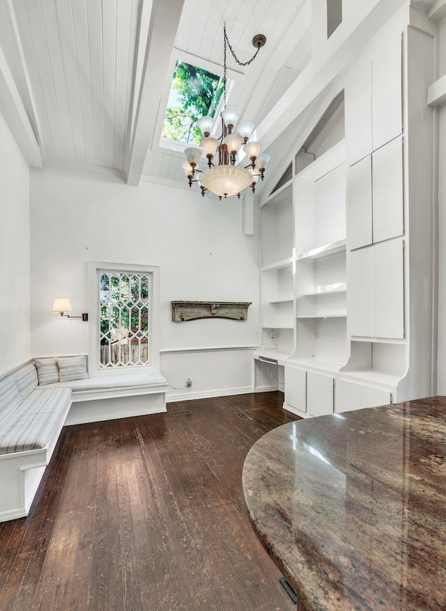 unfurnished living room with dark wood-type flooring, lofted ceiling with beams, a chandelier, and a wealth of natural light