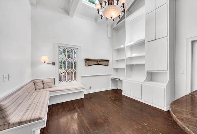 spacious closet featuring beam ceiling, a chandelier, a towering ceiling, and dark hardwood / wood-style floors