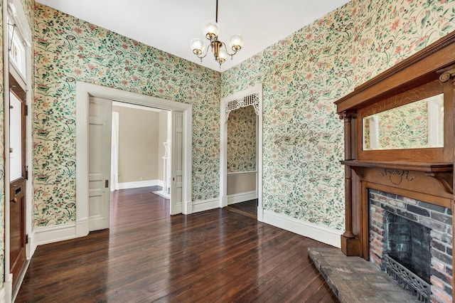 unfurnished living room featuring a fireplace, dark wood-type flooring, and a chandelier