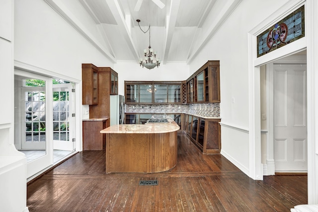 kitchen with hanging light fixtures, stainless steel fridge, dark hardwood / wood-style floors, an inviting chandelier, and decorative backsplash