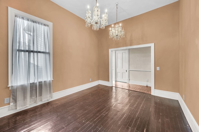 empty room with wood-type flooring and a notable chandelier