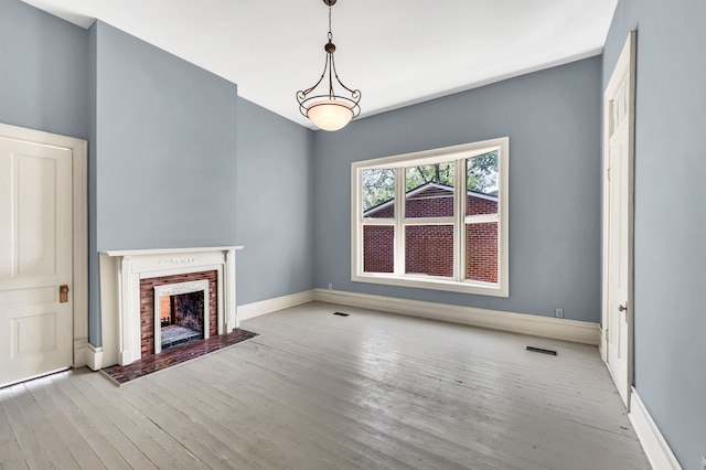 unfurnished living room featuring a brick fireplace and light hardwood / wood-style flooring