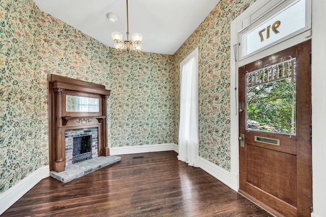 foyer featuring a brick fireplace, dark hardwood / wood-style floors, and a chandelier