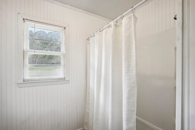 bathroom with wooden walls, curtained shower, and a textured ceiling