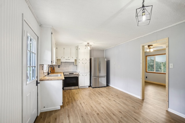 kitchen with ornamental molding, light wood-type flooring, stainless steel appliances, and white cabinets