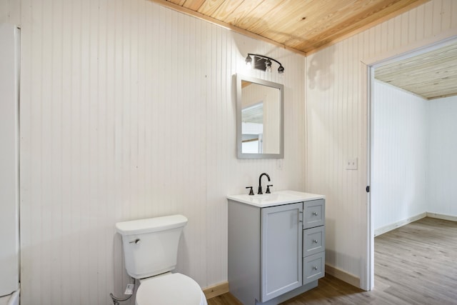 bathroom featuring toilet, wood-type flooring, wood ceiling, wooden walls, and vanity