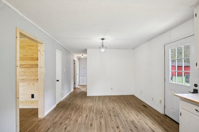 unfurnished room featuring ornamental molding, wooden walls, light hardwood / wood-style floors, and a textured ceiling