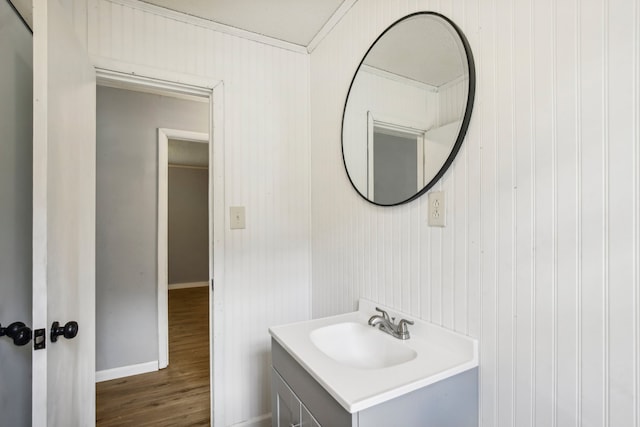 bathroom featuring hardwood / wood-style flooring, wooden walls, crown molding, and vanity