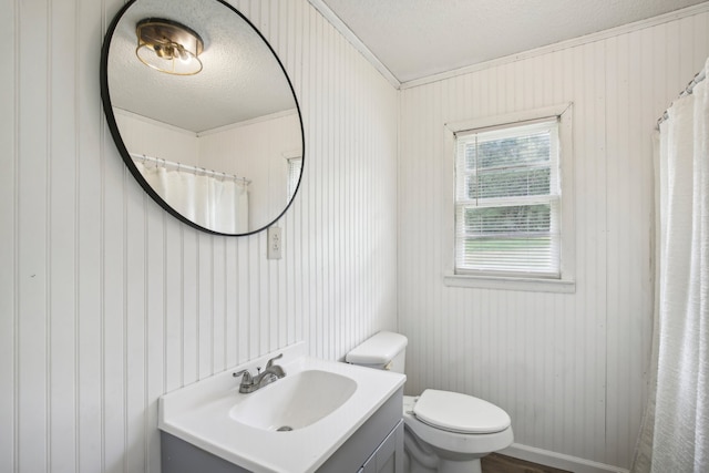 bathroom with wood walls, a textured ceiling, vanity, and toilet