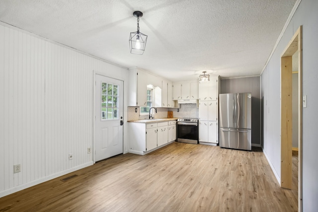 kitchen featuring light wood-type flooring, stainless steel appliances, tasteful backsplash, white cabinets, and decorative light fixtures