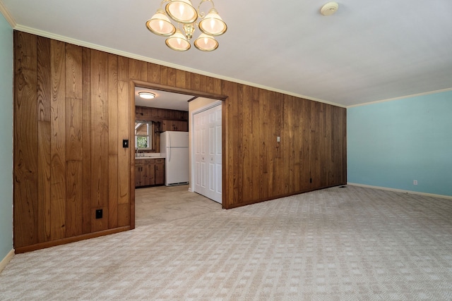 unfurnished room with light carpet, wooden walls, crown molding, and a chandelier