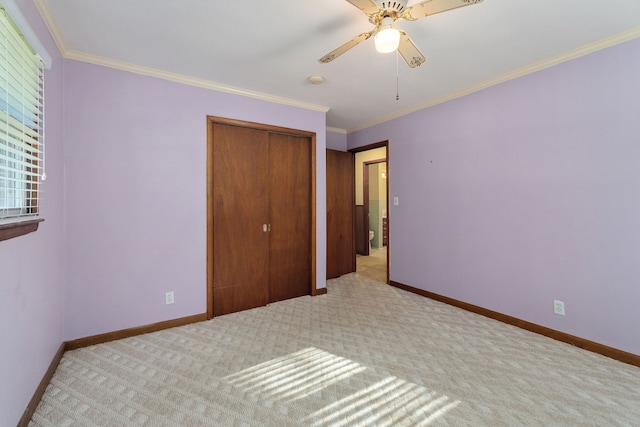 unfurnished bedroom featuring a closet, light colored carpet, crown molding, and ceiling fan