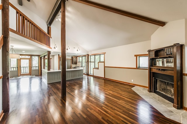 unfurnished living room with beamed ceiling, a fireplace with flush hearth, wood finished floors, and high vaulted ceiling