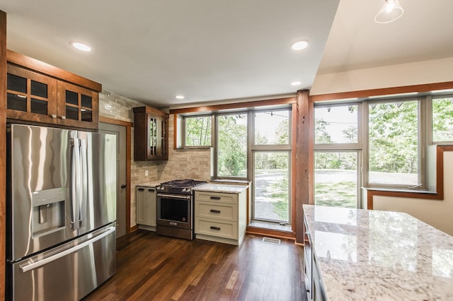 kitchen featuring visible vents, appliances with stainless steel finishes, light stone countertops, dark wood-style floors, and glass insert cabinets