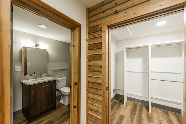 bathroom with vanity, wooden walls, hardwood / wood-style floors, and toilet