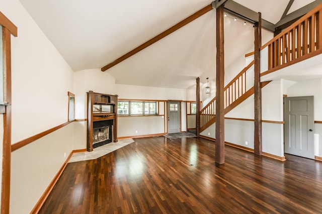 unfurnished living room with a fireplace with flush hearth, wood finished floors, stairway, baseboards, and beamed ceiling