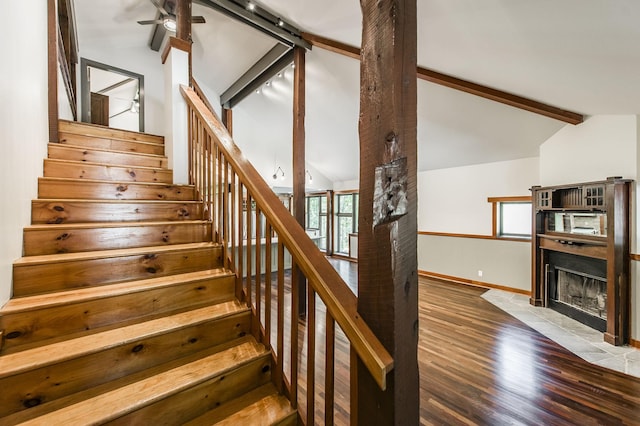 stairs with baseboards, lofted ceiling with beams, wood finished floors, and a tile fireplace