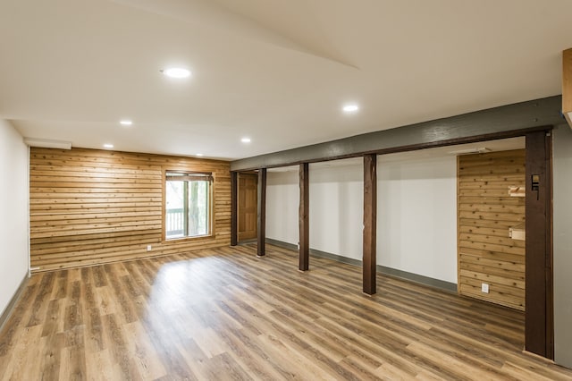 basement featuring hardwood / wood-style floors and wooden walls