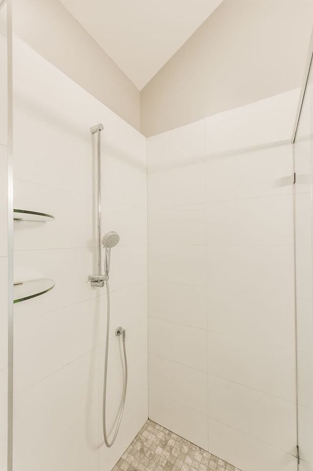 bathroom with vaulted ceiling and tiled shower