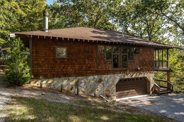 view of front of house featuring gravel driveway, roof with shingles, and a garage