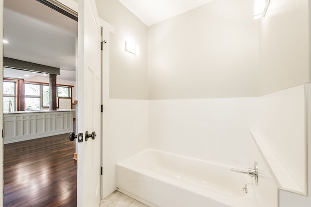 bathroom with hardwood / wood-style floors and a tub to relax in