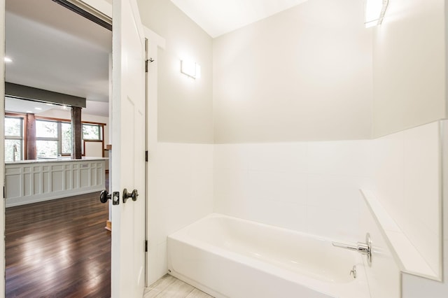 full bath featuring a tub and wood finished floors