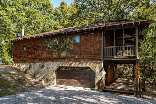 view of home's exterior featuring an attached garage, gravel driveway, and stone siding