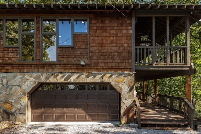 exterior space with a garage, stone siding, and a deck