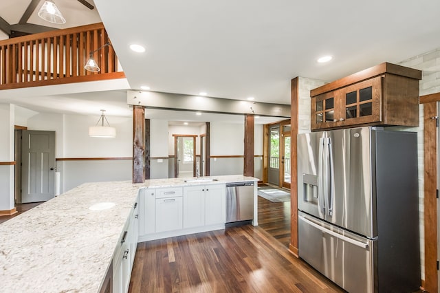 kitchen with dark wood-type flooring, light stone counters, hanging light fixtures, white cabinets, and appliances with stainless steel finishes