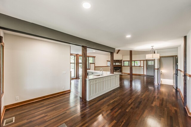 unfurnished living room with a sink, dark wood finished floors, recessed lighting, baseboards, and visible vents