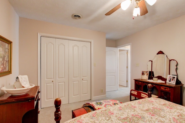 carpeted bedroom with ceiling fan, a textured ceiling, and a closet