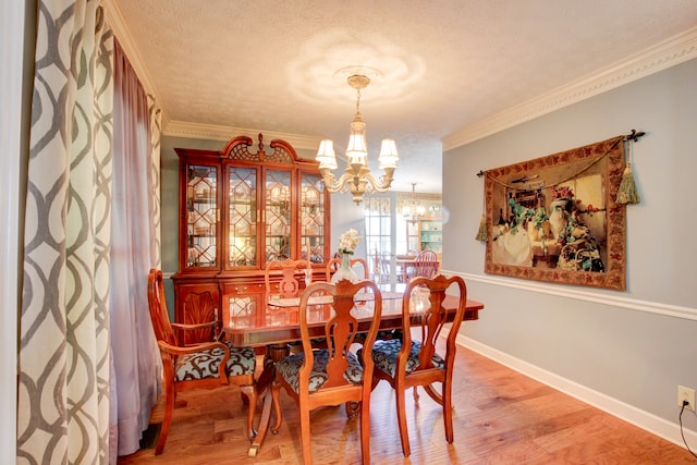 dining room featuring crown molding, hardwood / wood-style floors, an inviting chandelier, and a textured ceiling