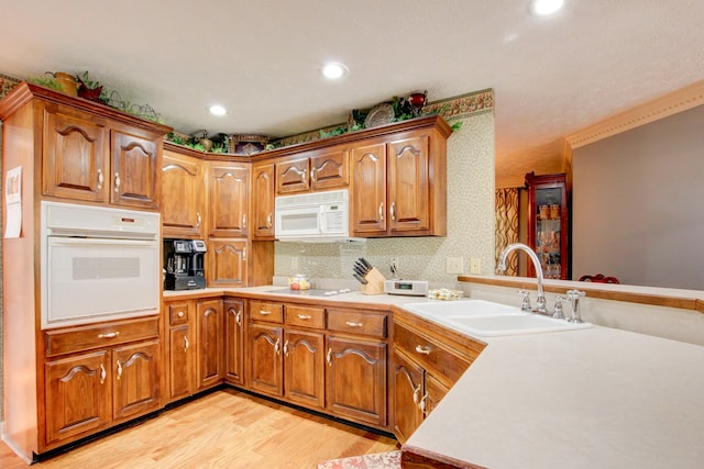 kitchen with decorative backsplash, white appliances, light hardwood / wood-style floors, and sink