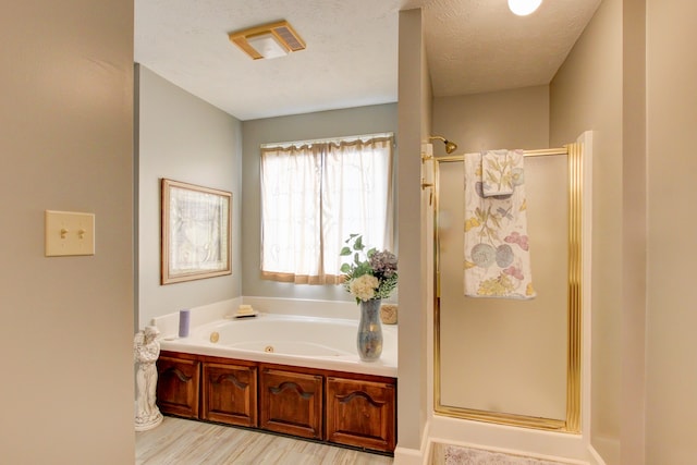 bathroom with hardwood / wood-style flooring, separate shower and tub, and a textured ceiling