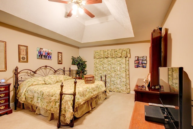 bedroom with ceiling fan, a raised ceiling, and carpet flooring