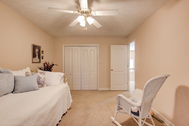 carpeted bedroom featuring ceiling fan, a closet, and a textured ceiling