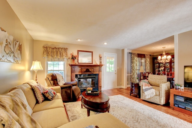 living room with a fireplace, an inviting chandelier, light wood-type flooring, and a healthy amount of sunlight