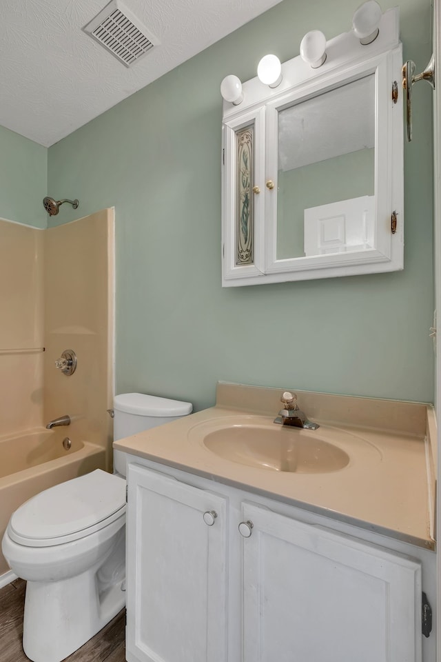 full bathroom featuring shower / bathtub combination, vanity, hardwood / wood-style flooring, toilet, and a textured ceiling