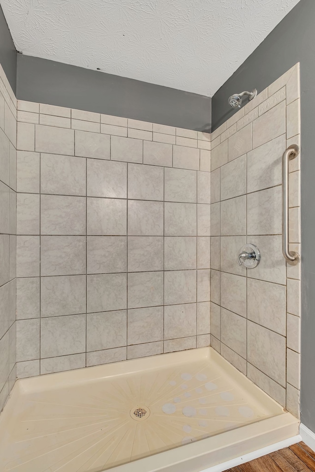 bathroom with a tile shower, hardwood / wood-style floors, and a textured ceiling